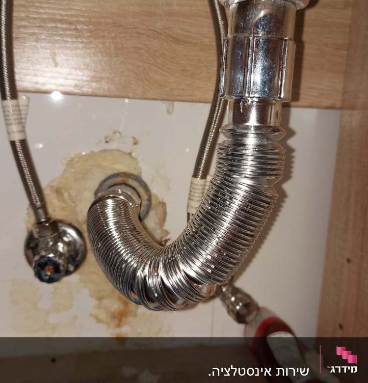 צינור מתכת מתחת לכיור עם חיבורי ברגים